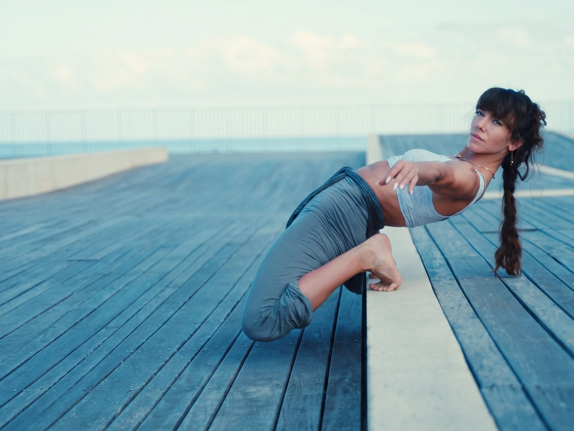 Yona Shavin holding a low, controlled kneeling lean-back on the boardwalk at sunset